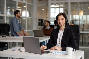 Young friendly operator woman agent with headsets working in call center in contemporary office - 793703540