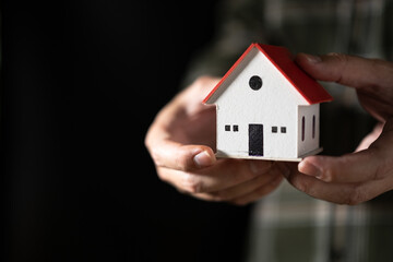 Man hand holding a house model in his hand,The concept of owning a house or mortgaging real estate.	