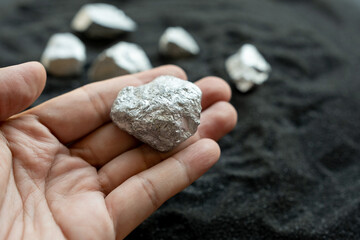 The hands of men are holding at the silver or platinum or rare earth minerals ore in their hands from the mine