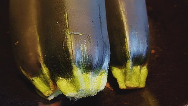 Close up of three whole fresh zucchini also known as baby marrow, courgette, summer squash. Window light reflecting on zucchini. Kitchen interior. Indoor studio lighting. . High quality 4k footage