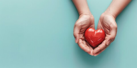 two hands holding a red heart on a light blue background