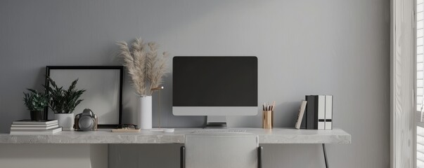 Minimalist home office with grey desk, computer and grey books on light grey wall background. Home interior design of modern work space 
