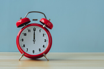 Red vintage alarm clock on the table with blue background.Time concept. Copy space.