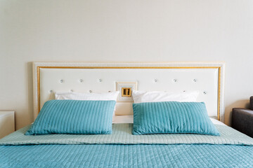Aqua bedding and pillows on wood bed frame in rectangular bedroom fixture
