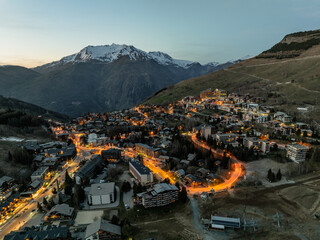 Town in the alps mountains during sunset.Aerial drone photo Blue Hour French alps in winter, Rhone Alpes in France Europe. Les deux alpes village in spring time.Winter French Alpes town from drone