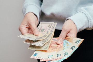 Exchange US dollar or American dollars (USD) for EUR money. Woman counts banknotes. Woman hands counting money American dollars and euro. A lot of money in women's hands.