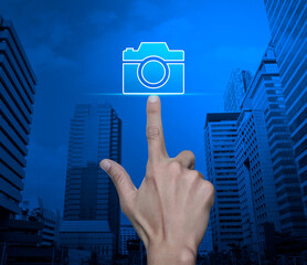 Hand pressing camera flat icon over modern city tower and skyscraper, Business camera service shop concept