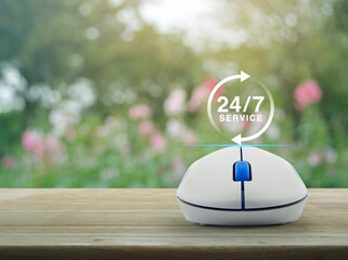 24 hours service icon with wireless computer mouse on wooden table over blur pink flower and tree in park, Business full time online service concept