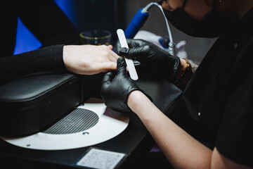 Woman in gloves doing manicure on man's hand while filing nails. - obrazy, fototapety, plakaty