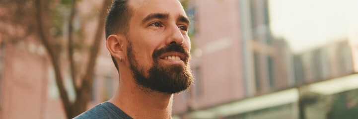 Obraz premium Young smiling man with beard walking and looking around at the old city background, Panorama