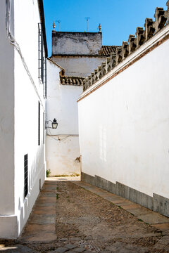This image shows the traditional white-walled architecture of Cordoba, Andalusia, Spain The narrow alley and stark walls represent the historic urban landscape of Europe travel