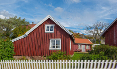 red typical house with white fence in front in a sweden village - 793728533