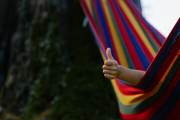 Thumbs up. A child in a hammock in nature. The tourist season.