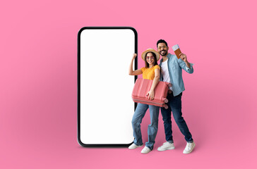 Playful couple presenting a large smartphone screen - obrazy, fototapety, plakaty