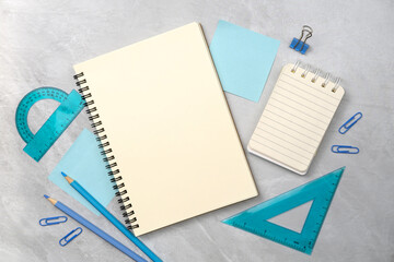 Notebook and light blue stationery on stone texture background. Work desk space