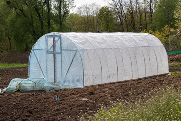 Small garden greenhouse on freshly tilled soil