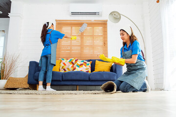 Two Asian young professional cleaning service women worker team working in the house. Girl...