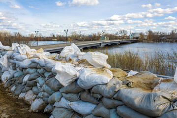 A wall of white sandbags has been erected as a barricade for flood protection, with a flooded bridge in the background in the city of Kurgan, Russia.	