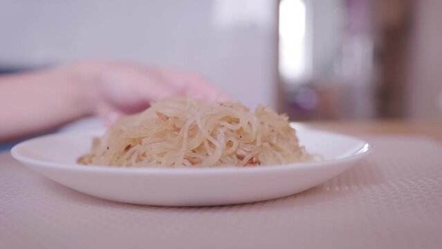 Rice noodles in white blue close-up.A human eats rice noodles.