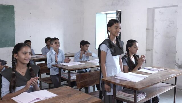 Indian students clapping for intelligent schoolboy at classroom, Children give applause for brilliant girl. Rural india. - Powered by Adobe