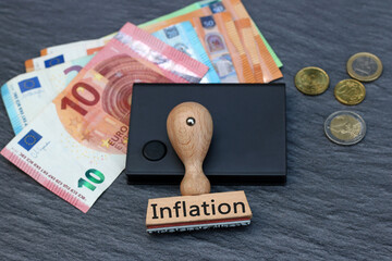 Das Wort Inflation auf einem Stempel mit Euro-Banknoten