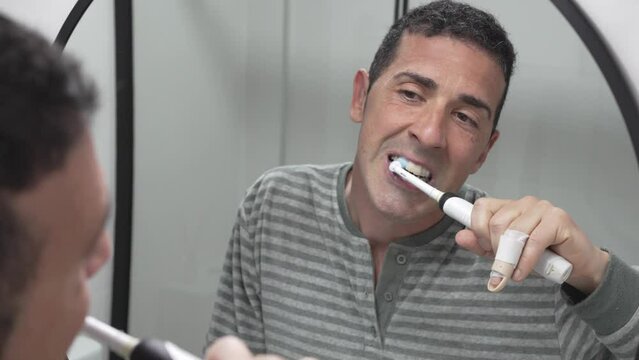 Meticulous Young Man Brushing Aligned Teeth With Electric Toothbrush. Daily Oral Hygiene Concept.