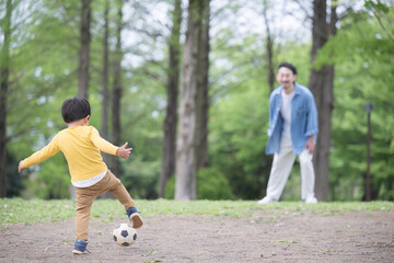サッカーボールを蹴る男の子と遊ぶ父親　顔無しの後ろ姿