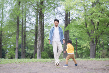 サッカーボールを蹴る男の子と遊ぶ父親
