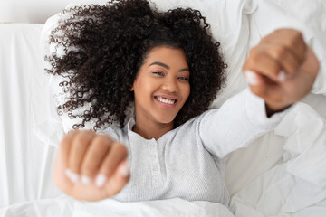 Smiling Young Woman Stretching in a Cozy White Bed