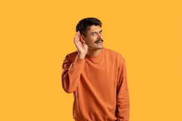 Man in Orange Shirt Holding Hand to Ear