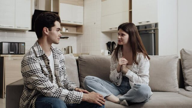 Young caucasian woman sitting on a couch at home and talking with her attentive and listening partner. Concept of happiness and support in the couple relationship