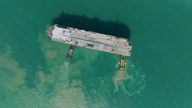 Aerial view Tug boat pushing Large RoRo Roll on Roll off to loading dock or quayside for carrier vessels convey cars and trucks into and out of the world market. 4k video
