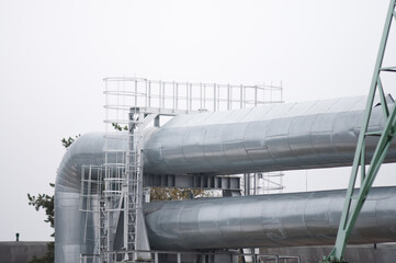 pipelines and power lines close-up against a gray sky