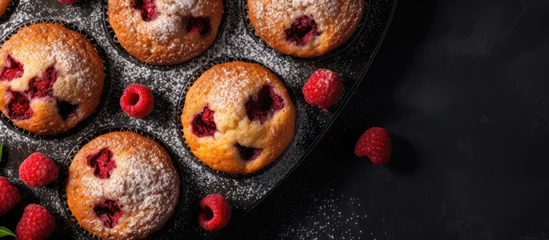 Tuinposter Muffin pan with raspberries and powdered sugar © Ilgun
