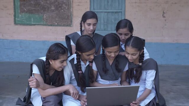 Group of Rural indian schoolgirls using laptop, Learn computer modern technology at elementary school. Smart Kids, online curiosity Knowledge, Village India.