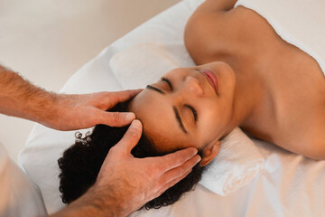 Fototapeta na wymiar Therapist providing temple massage to relaxing woman
