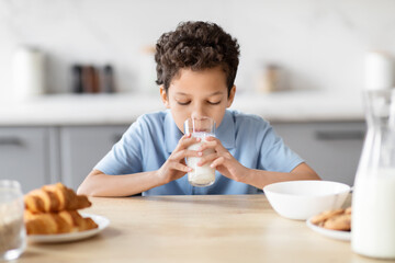 Boy enjoying a glass of milk in kitchen