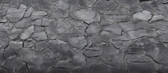 Close-up of weathered black stone wall with fissures