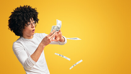 Happy young man throwing out money banknotes