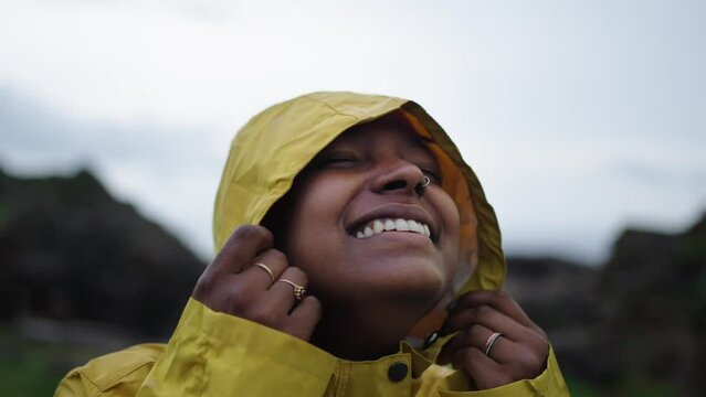 Close-up portrait of an African American young woman enjoying the rain and looking to the camera with a toothy smile. People grateful for the water.