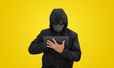 Hacker in hooded using tablet to hacking data isolated on yellow background. Image with Clipping path. - 793792595
