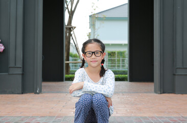 Portrait of Asian young girl wearing glasses with looking camera while sitting in the garden. - 793793174