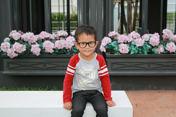 Asian little boy child wearing glasses while sitting in the garden. - 793793309