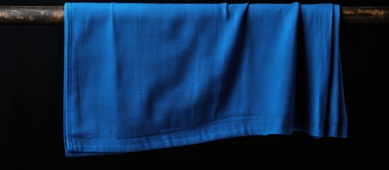 Blue towel on wooden pole against black background