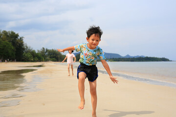 Happy Asian little boy child and girl kid having fun running on tropical sand beach at sunrise. Happy family sister and brother enjoy in summer holiday. - 793794358