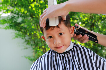 Cutting hair of Asian little boy with Hair Clipper in the garden - 793794538