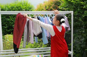 Asian girl hanging the laundry on a clothes rail at the garden near house. - 793794961