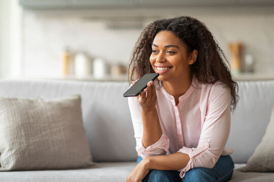Smiling Woman Using Voice Command on Smartphone at Home