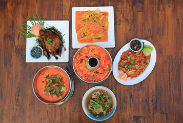 Varieties of Thai food on wooden table background. Tom Yum. Periwinkle curry. Pork bones soup. Stir fried crab. Sliced roast duck. Grilled Peking Duck. Top view. - 793795905