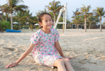 Portrait of smiling Asian young girl child lying on beach sand at summer holiday. - 793796970